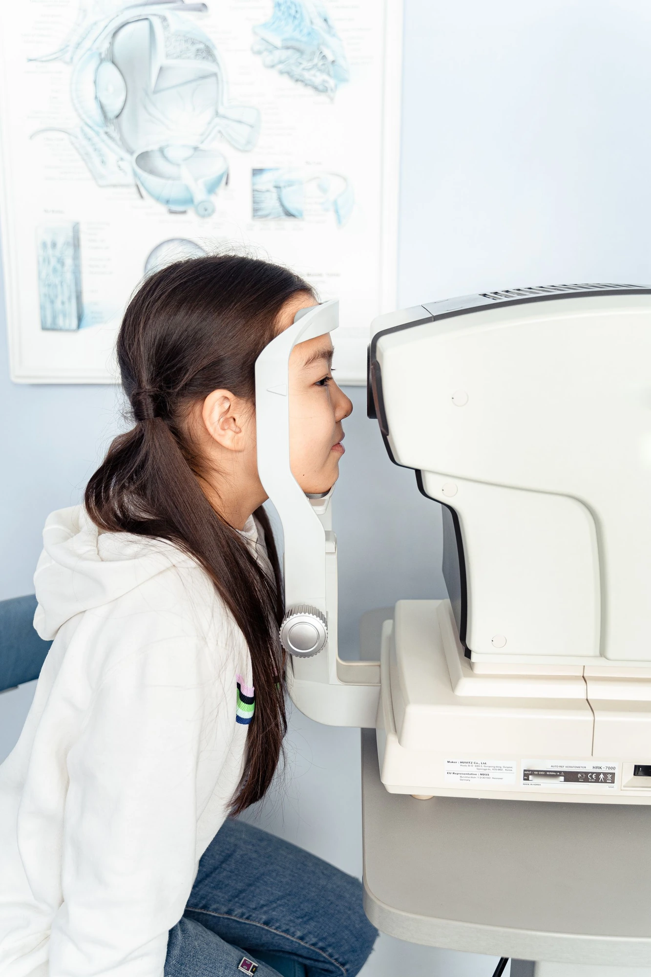 A child seated at eye examination equipment in an illustrative stock photograph