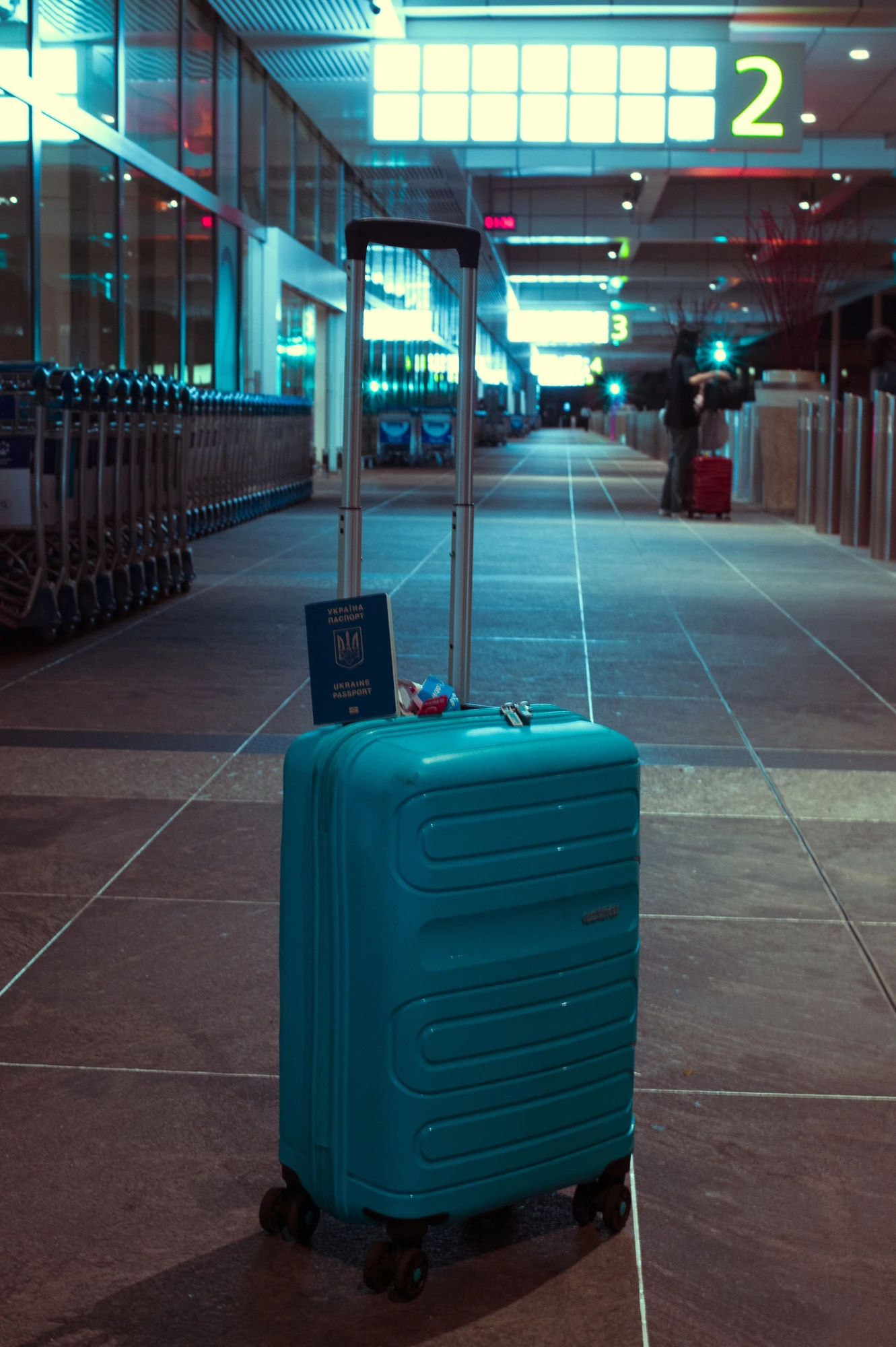 A blue suitcase standing in an airport terminal
