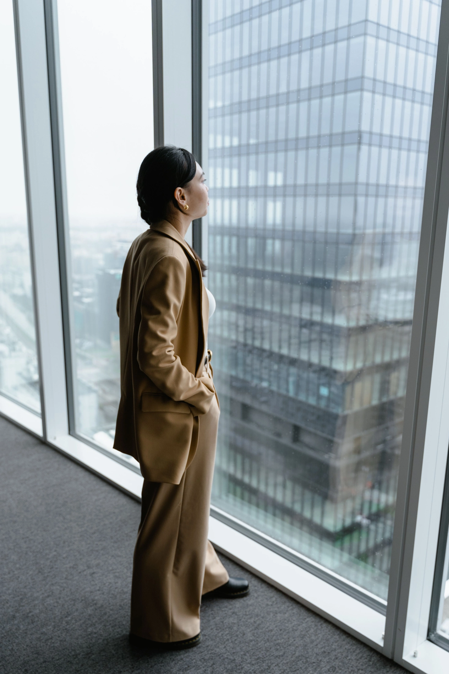 A woman in a suit looks through a glass office window. Illustrative stock photograph.