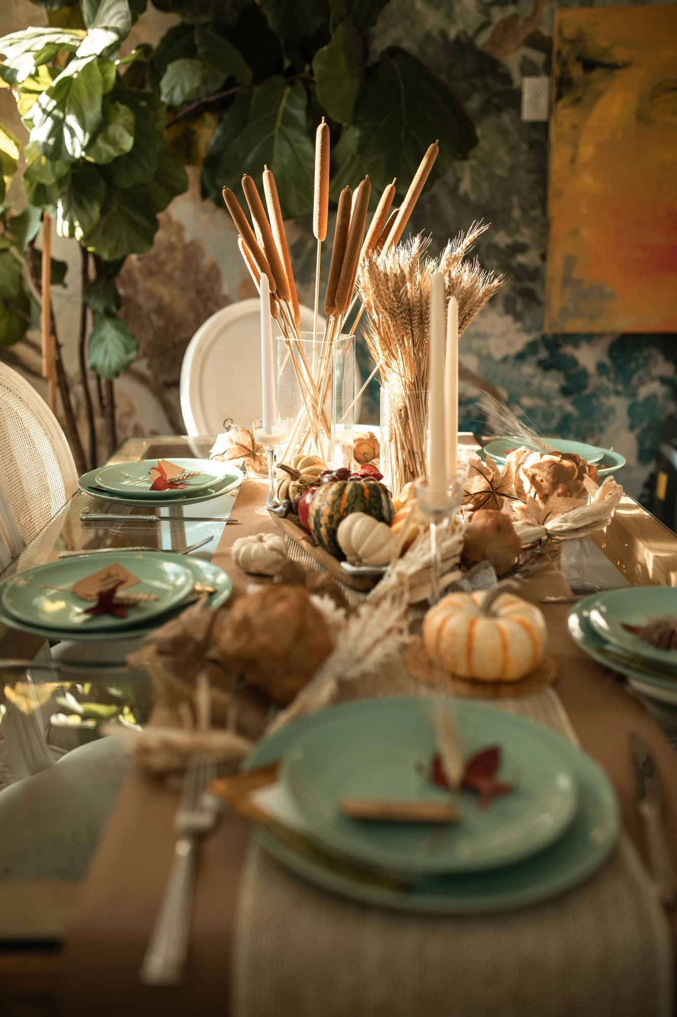 An autumn dining table arranged with plates, pumpkins, and seasonal decorations